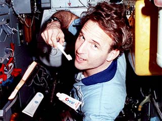 NASA/Mir-23 researcher Jerry Linenger takes care of personal hygiene in the Spektr module. Linenger brushes his teeth and floats toothpaste, deodorant, brush and Astro gel in front of himself. 